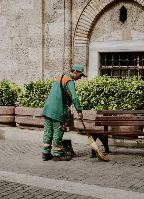 Side view of a young ethnic man in uniform mopping the floor while working inside a retro-style restaurant